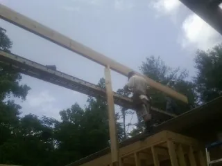 Carpenter setting a ridge beam over a new addition frame — Ice Dam Removal by Roofing Brothers in Rochester