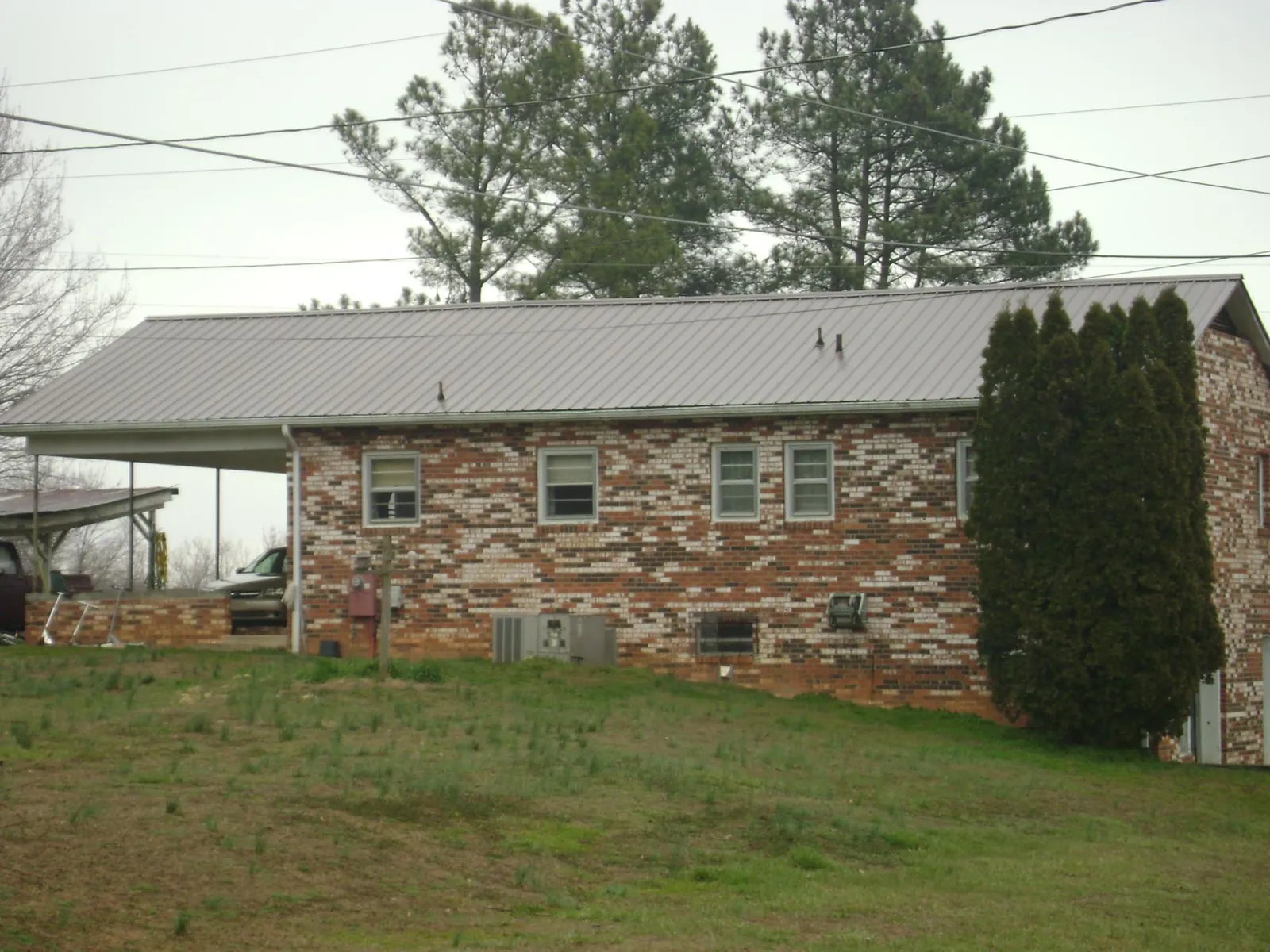 Gray metal roof on a brick split level home with a carport in Rochester